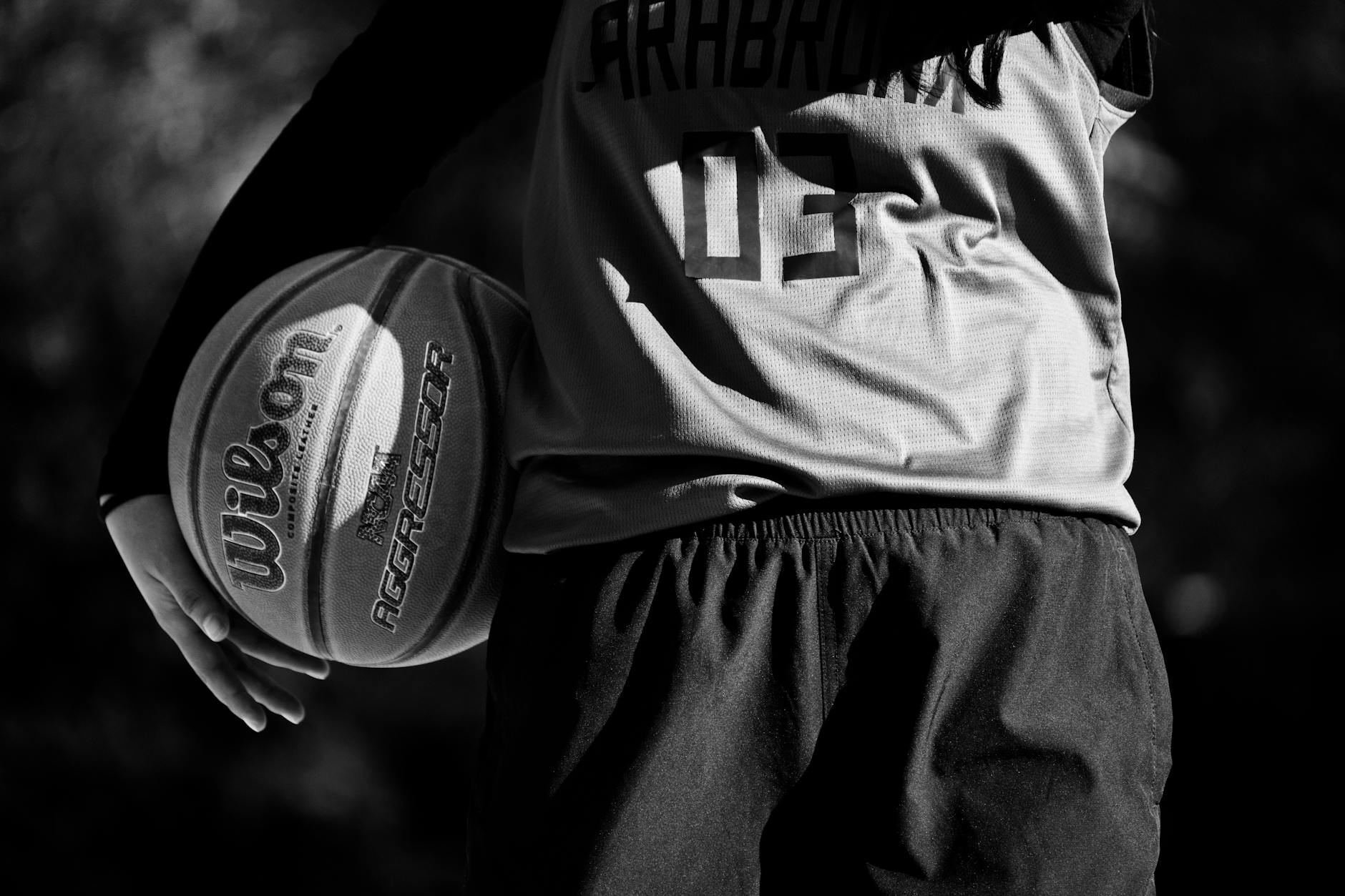 grayscale photo of a person holding a basketball